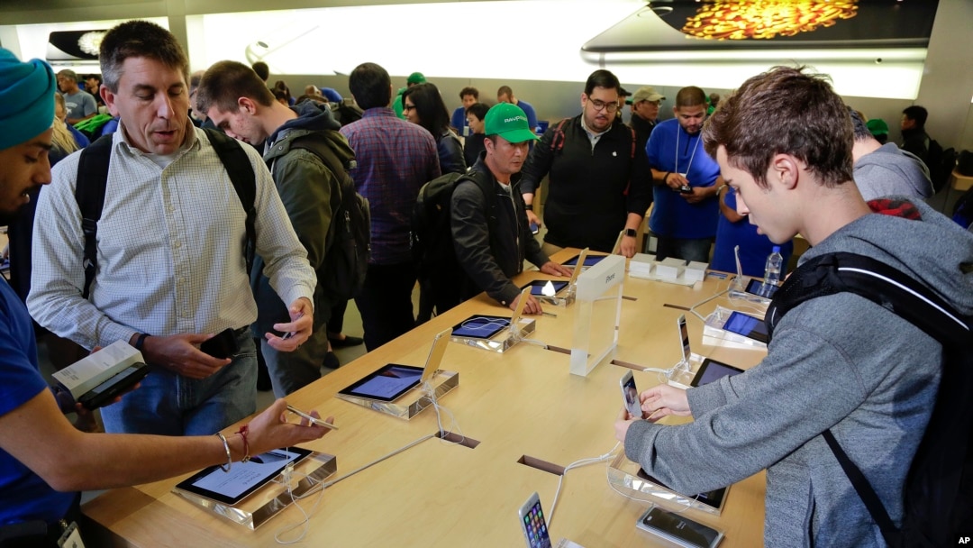 FILE - Shoppers examine products at an Apple store in New York. 