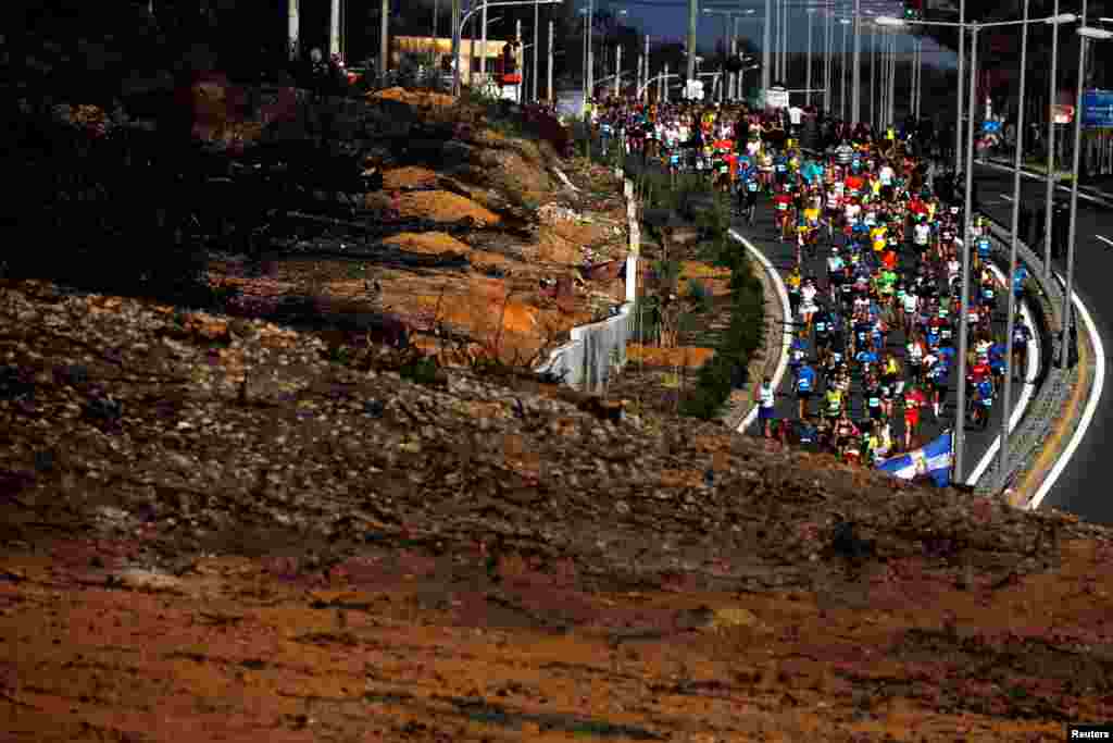 Runners race past a hill burned in Greece's deadliest wildfire in July, during the 36th Athens Classic Marathon, in the village of Mati, near Athens, Nov. 11, 2018.