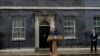New British Prime Minister Liz Truss speaks outside Downing Street as her husband, Hugh O'Leary, listens, in London, Sept. 6, 2022 after returning from Balmoral in Scotland where she was formally appointed by Britain's Queen Elizabeth II. 