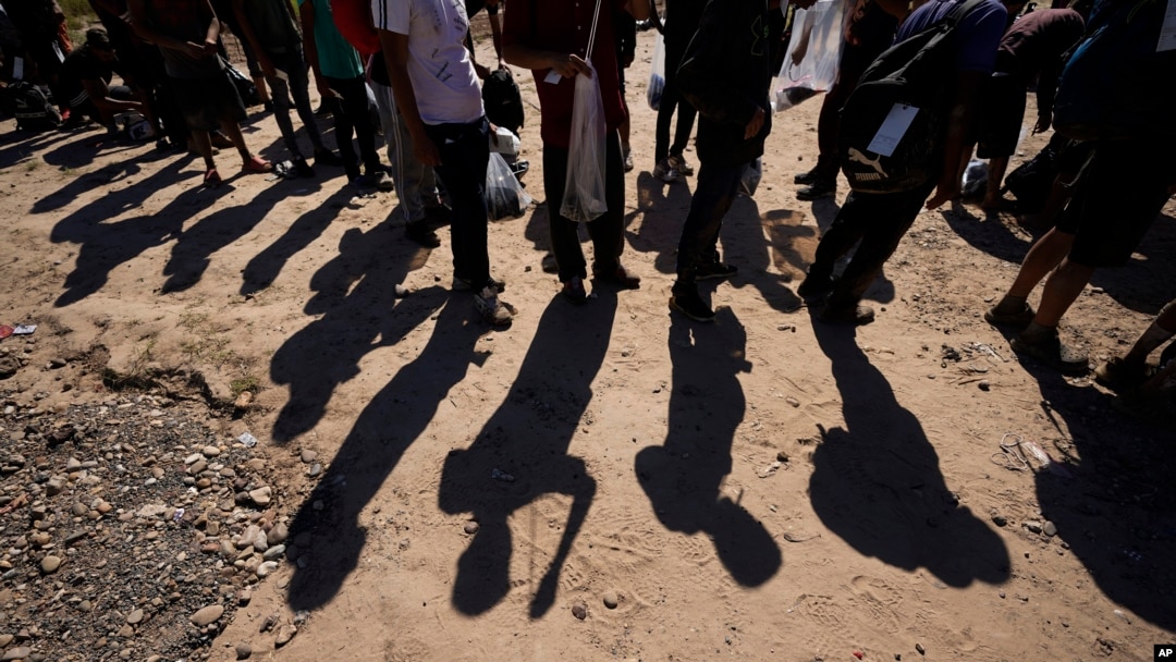 FILE - Migrants wait to be processed by U.S. officials after crossing the Rio Grande and entering the U.S. from Mexico, in Eagle Pass, Texas, Oct. 19, 2023. U.S. President Joe Biden and presidential candidate Donald Trump will visit the U.S./Mexico border soon — but separately.