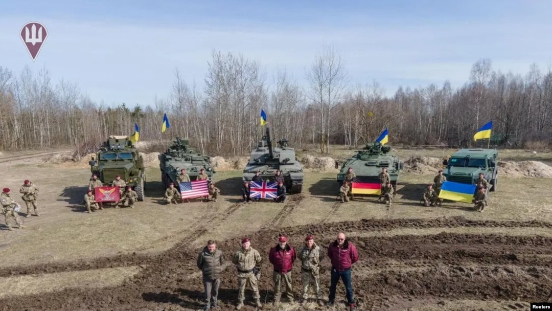 Funcionarios de defensa ucranianos posan frente a equipos militares suministrados desde el extranjero, incluido un tanque de batalla británico Challenger 2, en un lugar no identificado en Ucrania, el 27 de marzo de 2023.