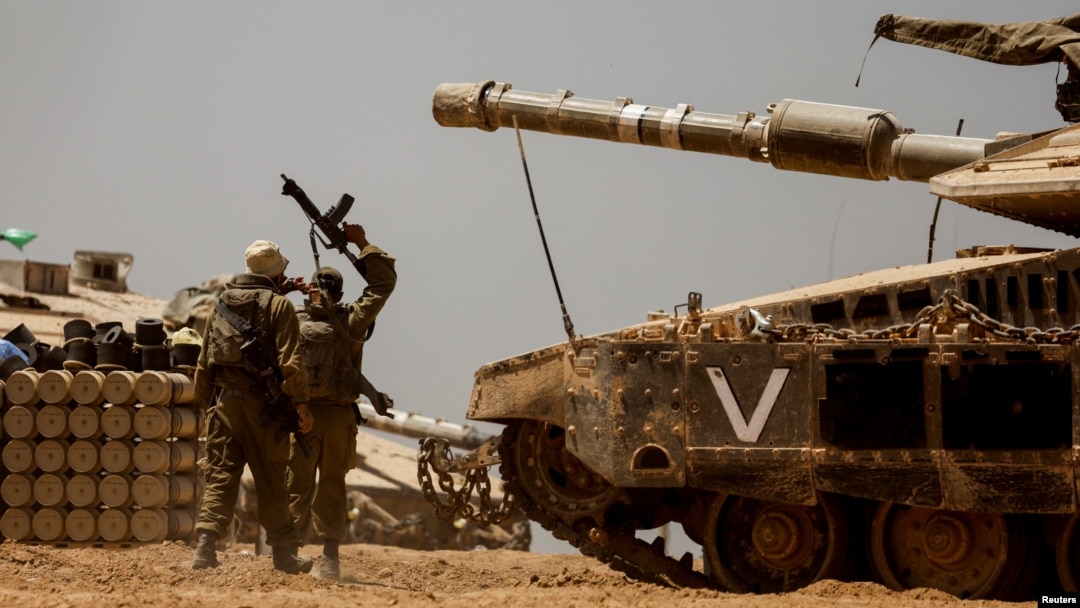 Israeli soldiers walk near a tank and ammunition piles near the Israel-Gaza Border, in southern Israel, May 9, 2024.