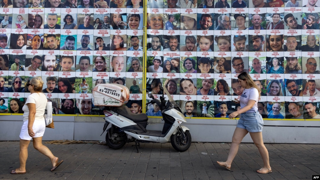 People walk past posters of Israelis held hostage by Palestinian militants in Gaza since the October 7 attacks, in Tel Aviv on Aug. 11, 2024.