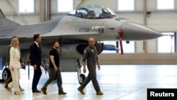 Ukrainian President Volodymyr Zelenskiy and Dutch Prime Minister Mark Rutte walk near an F-16, in Eindhoven, Netherlands, Aug. 20, 2023. 