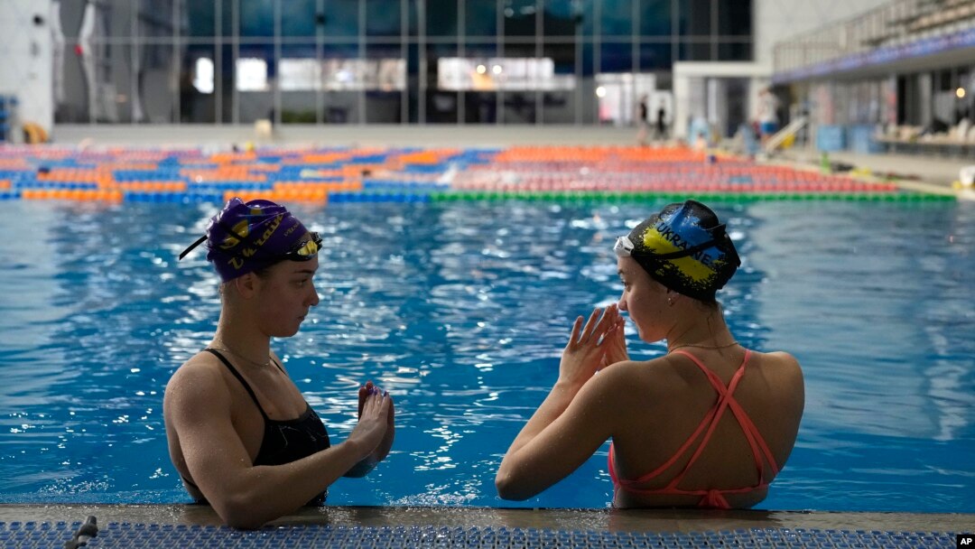 Las hermanas ucranianas Maryna, a la izquierda, y Vladyslava Aleksiiva hablan durante una sesión de práctica en Kiev, Ucrania, el martes 21 de febrero de 2023.