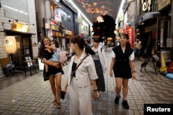 Rickshaw puller Shiori Yoshida, 28, and her daughter Yui, 3, walk to a restaurant for drinks with fellow pullers after work, at the Asakusa district in Tokyo, Aug. 17, 2023.