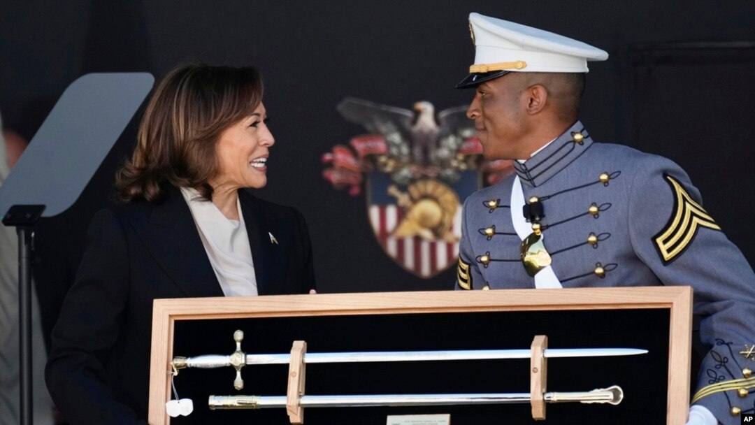 El cadete Melic Belong entrega a la vicepresidenta Kamala Harris un recuerdo durante la ceremonia de graduación de los cadetes de la academia militar de Estados Unidos en West Point, Nueva York, sábado 27 de mayo de 2023. (AP Foto/Bryan Woolston)