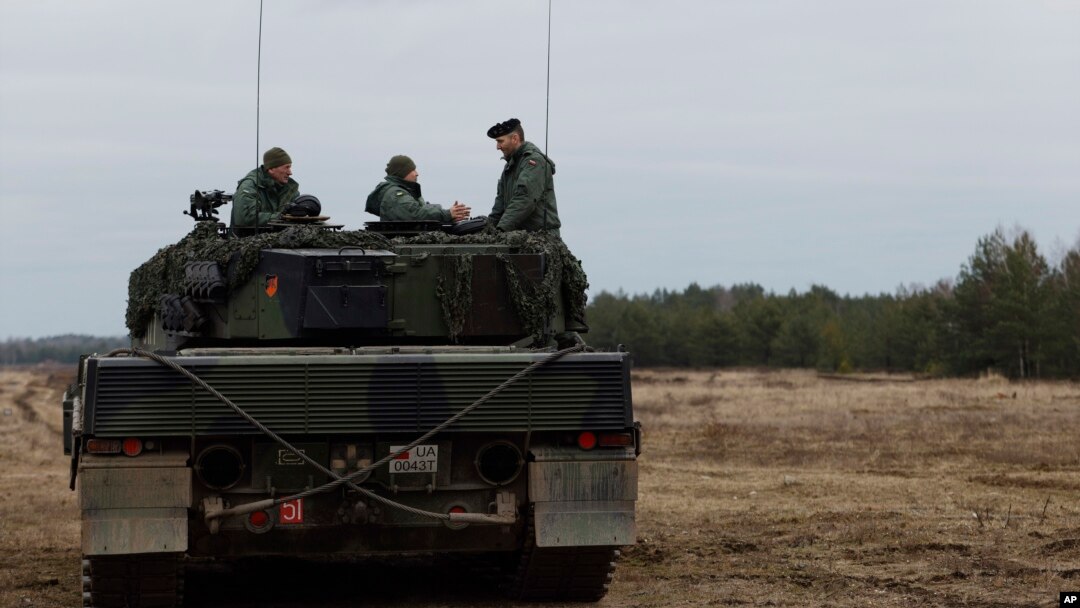 Soldados ucranianos y polacos se sientan encima de un tanque Leopard 2 durante el entrenamiento en una base militar y campo de pruebas en Swietoszow, Polonia, el 13 de febrero de 2023.