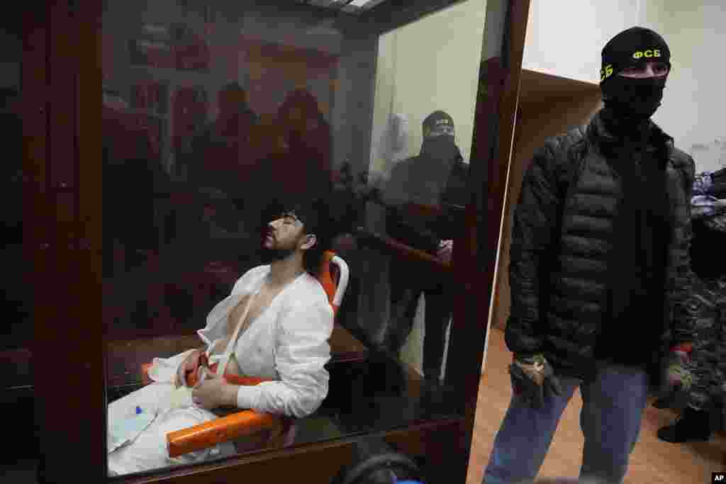 Mukhammadsobir Faizov, a suspect in Friday's shooting at the Crocus City Hall, sits in a glass cage in the Basmanny District Court in Moscow, Russia, March 24, 2024.