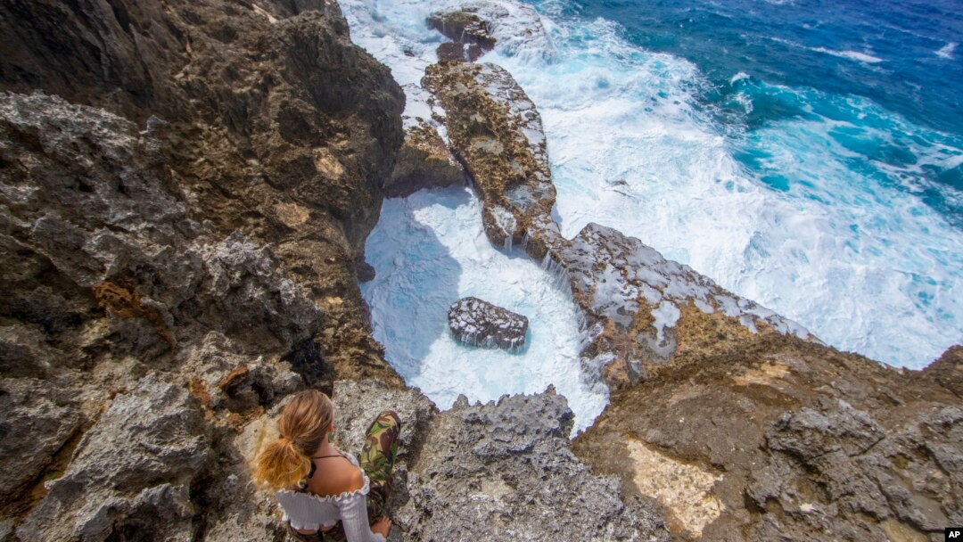 A person sits on a rock face overlooking the ocean in Niue in this 2018 photo. Prime Minister Dalton Tagelagi on Sept. 19, 2023, announced a plan in which individuals or companies can pay $148 to protect 1 square kilometer of ocean.