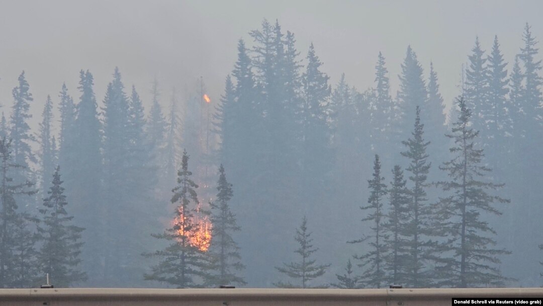 FILE - Flames and smoke rise from a wildfire visible from a highway in Jasper, Alberta, Canada, July 23, 2024, in this screen grab from a social media video. (Donald Schroll via Reuters)