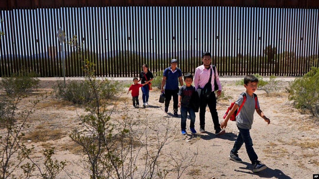 FILE - Migrants walk through the desert after crossing the border wall in the Tucson Sector of the U.S.-Mexico border, Aug. 29, 2023, near Lukeville, Ariz. 
