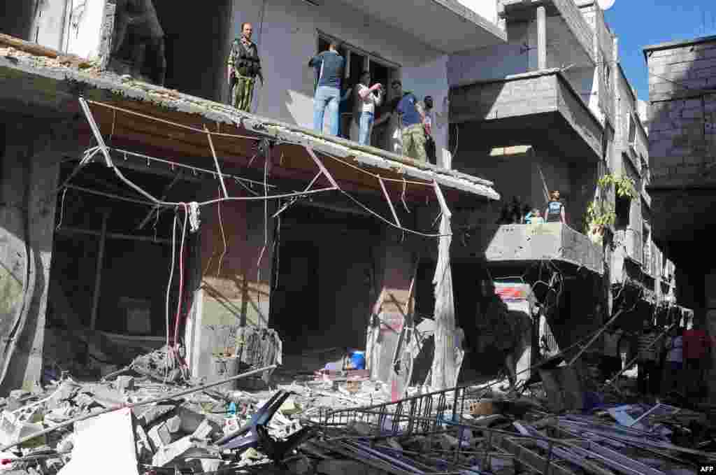Syrian citizens and security forces inspecting the sight of a car bomb attack in Damascus' Tadamun neighborhood.