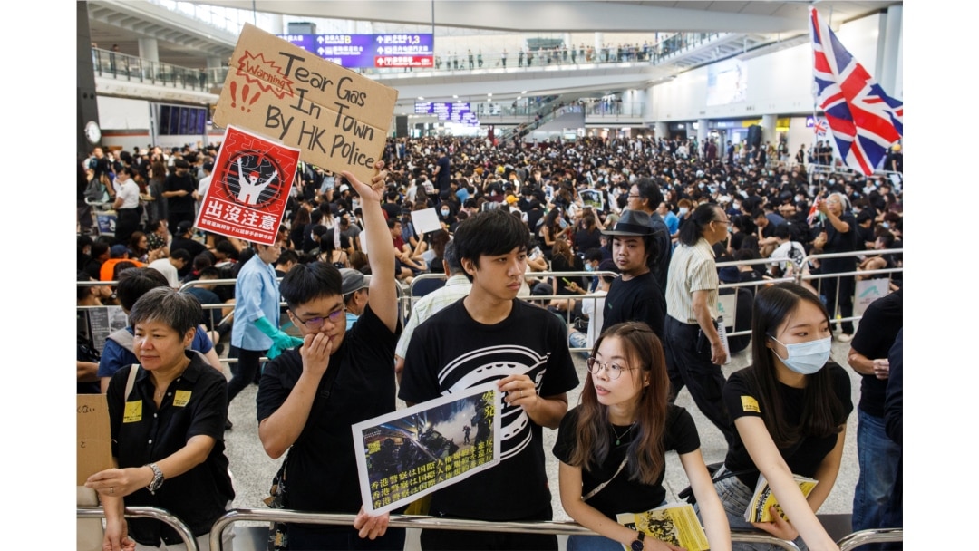 Anti-extradition bill protesters hold up placards for arriving travelers during a protest at the Hong Kong International Airport in Hong Kong, Aug. 9, 2019.