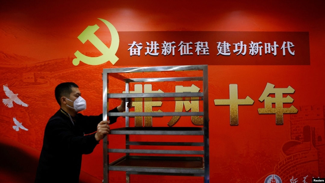 一名工作人員在北京一家酒店的中共二十大新聞中心走過宣傳中國領導人習近平的標語。（2022年10月19日）
