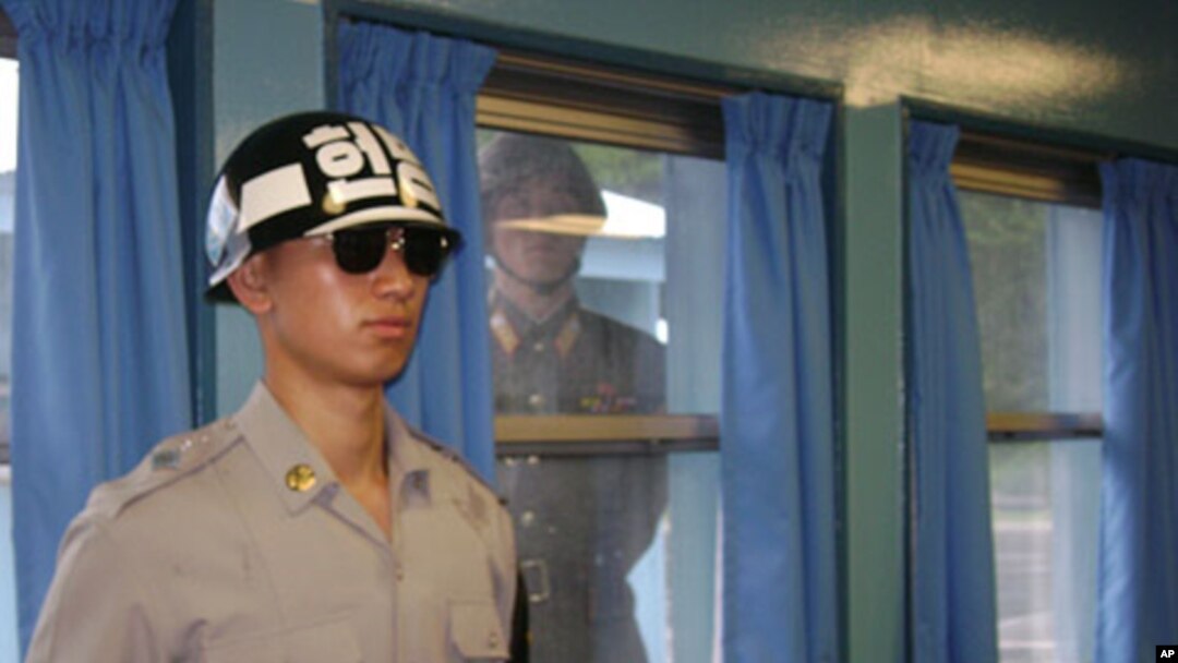 A North Korean soldier looks through a window as a South Korean stands guard at the U.N. truce village building that sits on the border of the Demilitarized Zone in Panmunjon, South Korea. (File)
