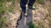 A farmer stands above a deep crack in the dried mud of an earthen embankment in his rice fields on the outskirts of Chongqing, China, Aug. 21, 2022.