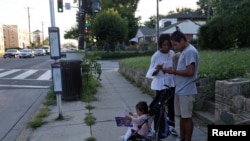 Noralis Zúñiga y Juan Camilo Mendoza esperan en una parada de autobús y consultan Google Maps para encontrar la ruta que los llevará de regreso al hotel en el que se hospedan con su hija Evangeline, de 1 año, después de visitar Mary's Center, en Washingto