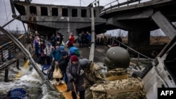 Evacuados cruzam uma ponte destruída em Irpin, noroeste de Kyiv, 7 Março 2022. 