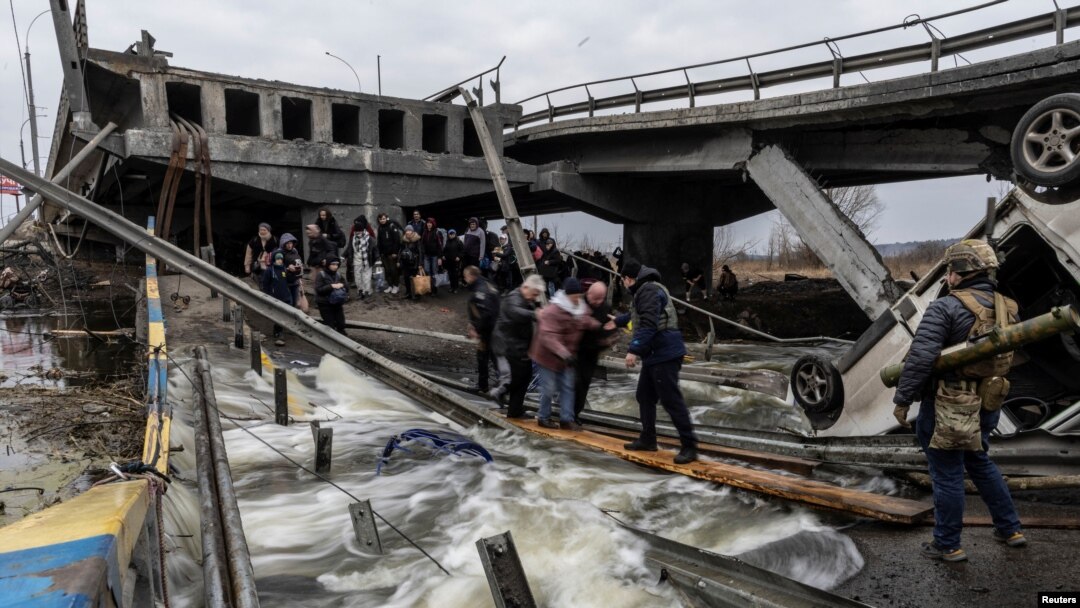 Los residentes locales cruzan un puente destruido mientras salen de la ciudad de Irpin, cerca de Kiev, la capital, después de días de intensos bombardeos en Ucrania por parte de fuerzas rusas, el 7 de marzo de 2022. 