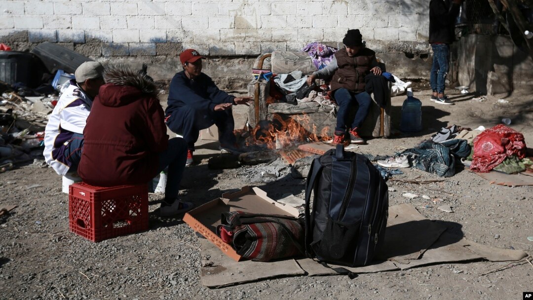 FILE - Migrants sit around a fire at a shelter on the U.S.-Mexico border in Ciudad Juarez, Mexico, Dec. 19, 2022.