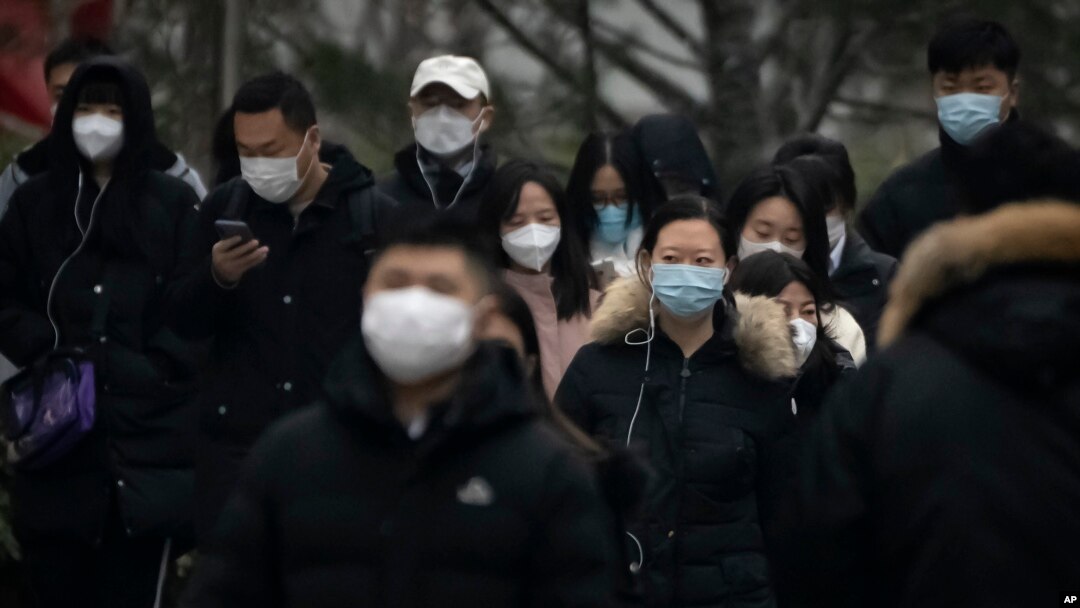 Commuters wearing face masks walk along a street in the central business district in Beijing, Jan. 12, 2023. 