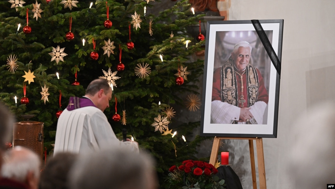 A photograph of late former Pope Emeritus Benedict XVI is seen during a Rosary prayer in the Catholic St Oswald church in his birth town Marktl am Inn, southern Germany, on Jan. 1, 2023, the day after his death. 