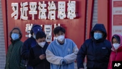 北京市民在宣傳習近平思想的標語牆前排隊等候進行核算檢測。 （2022年12月5日）