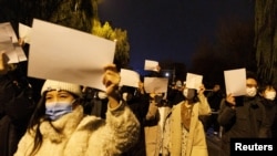 北京民眾手舉白紙上街遊行，抗議中國嚴厲的防疫政策，悼念烏魯木齊火災死難者。（2022年11月27日）