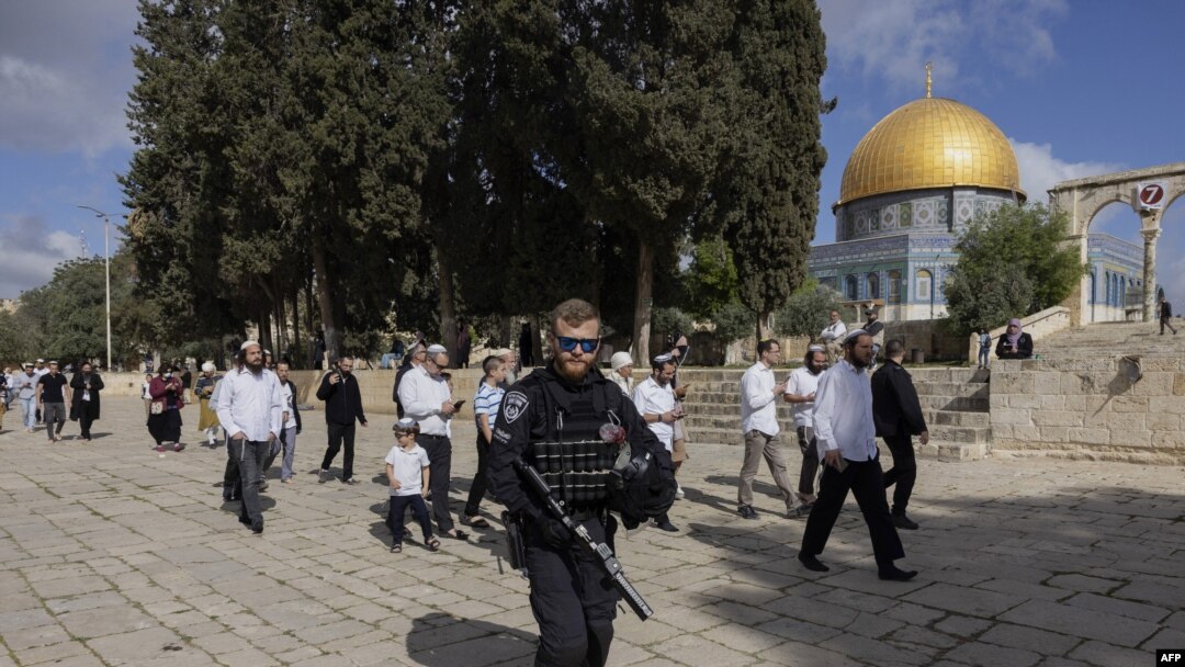 An Israeli security guard escorts a group of religious Jewish men and women during their visit to the Temple Mount, which is known to Muslims as the Haram al-Sharif, at the Aqsa mosques compound in the old city of Jerusalem, Apr. 20, 2022.