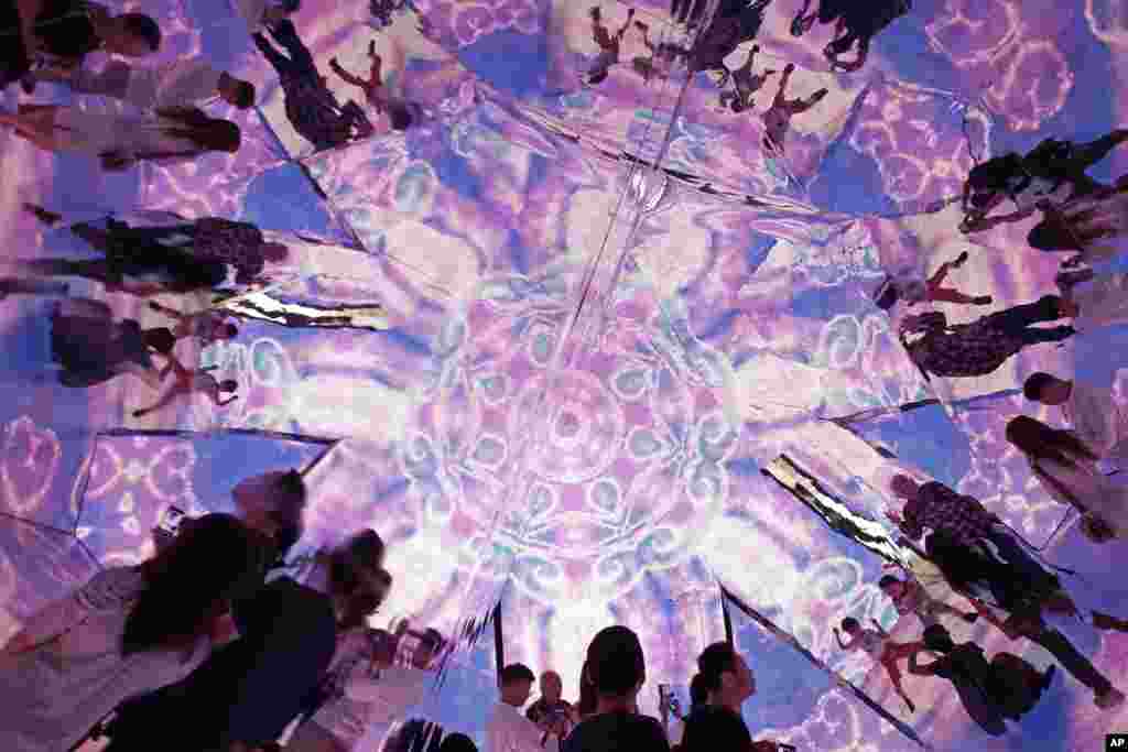 Visitors watch a light show inside the installation "Triangle Mirror Video Kaleidoscope" at a shopping mall in Hong Kong, to celebrate the upcoming Christmas festival season.