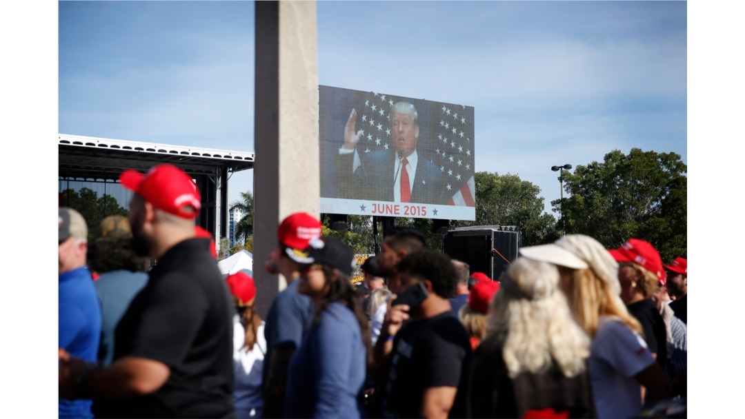 Supports watch a screen and wait in line before President Donald Trump's rally on Nov. 26, 2019, in Sunrise, Fla.