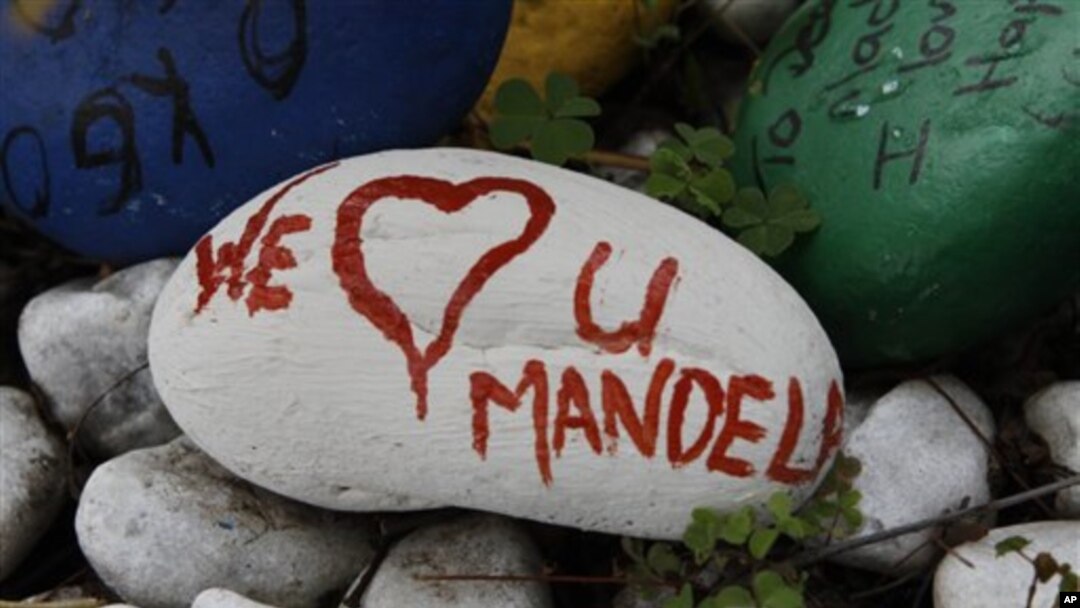 Uma pedra pintada com as palavras “Nós amamos-te Mandela’