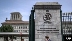 FILE - A man phones with his mobile while entering the World Trade Organization (WTO) headquarters in Geneva, Apr. 12, 2022. 