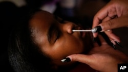 Danielle Mitchell gives her daughter, Brooklynn Chiles, 8, a COVID-19 antigen rapid test at home in Washington, Jan. 9, 2022.