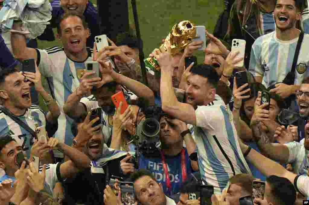 Argentina's Lionel Messi holds the winners trophy as he celebrates with fans after Argentina won the World Cup final soccer match against France at the Lusail Stadium in Lusail, Qatar, Dec. 18, 2022.
