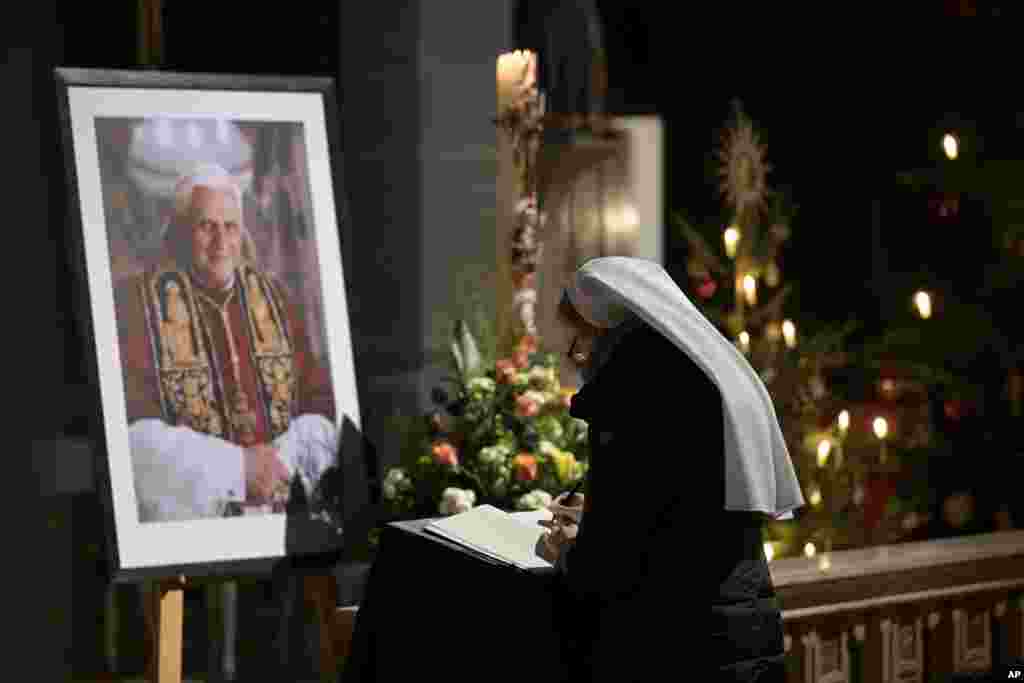 A person signs a book of condolence for Pope Emeritus Benedict XVI at the Saint Magdalena church in Altoetting, Germany, Dec. 31, 2022. Pope Emeritus Benedict XVI, the German theologian who will be remembered as the first pope in 600 years to resign, has died, the Vatican announced Saturday. He was 95. 