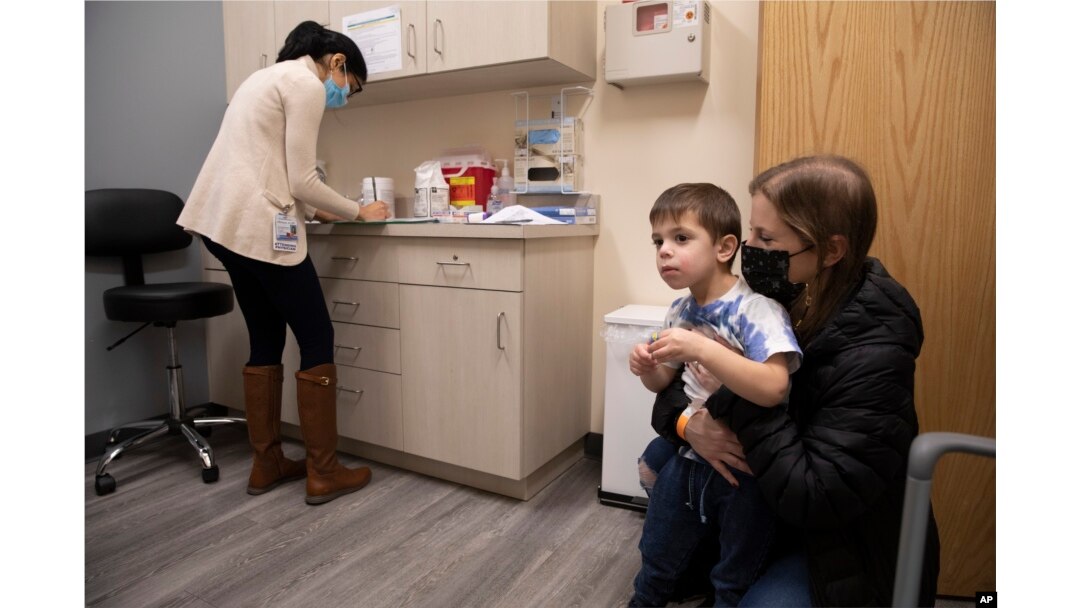 FILE - Ilana Diener holds her son, Hudson, 3, during an appointment for a Moderna COVID-19 vaccine trial in Commack, N.Y. on Nov. 30, 2021. (AP Photo/Emma H. Tobin, File)
