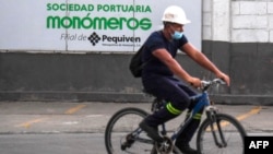Un trabajador pasa en bicicleta junto a un letrero de la empresa venezolana de fertilizantes Monómeros, en Barranquilla, Colombia, el 9 de octubre de 2021.