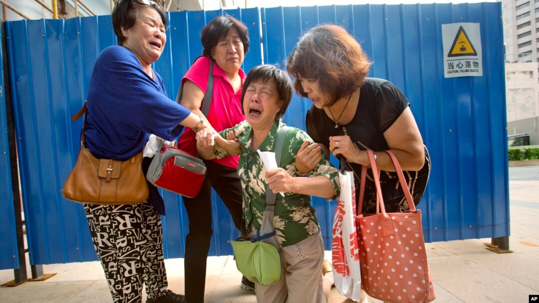 FILE - Bao Lanfang, second from right, whose daughter-in-law, son, and granddaughter were aboard Malaysia Airlines Flight 370, kneels in grief while speaking to journalists outside the company's offices in Beijing, Thursday, Aug. 6, 2015. 