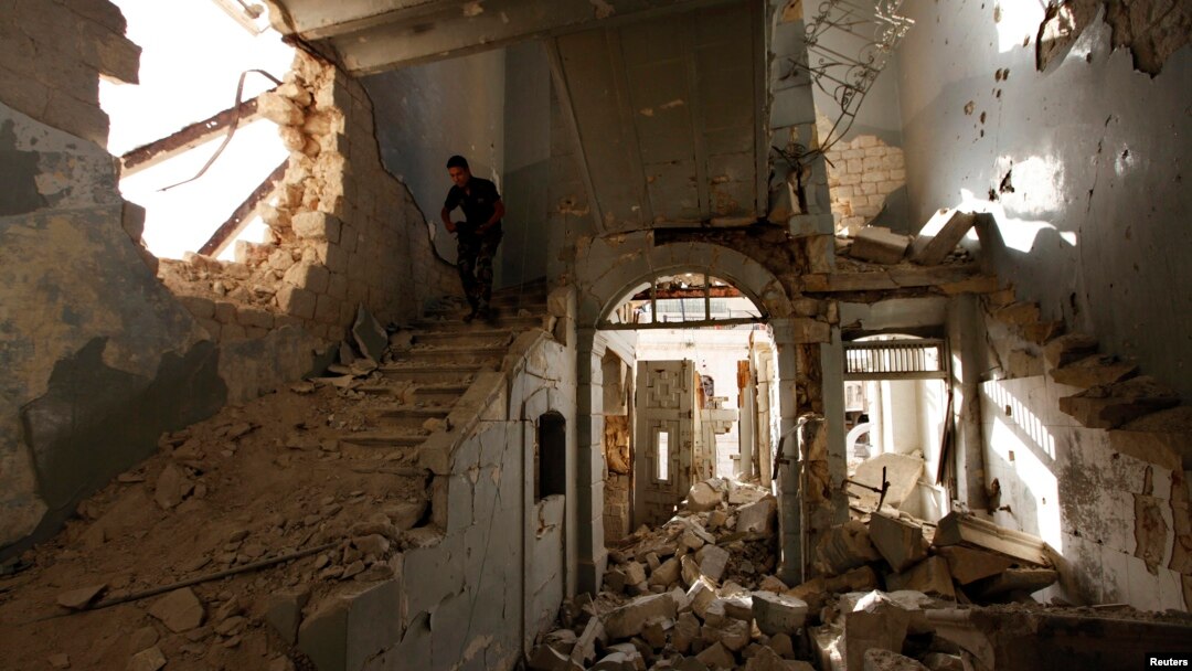 A Free Syrian Army fighter carries his weapon as he walks down the stairs of the damaged former Immigration and Passport building in Aleppo, Oct. 2, 2013.