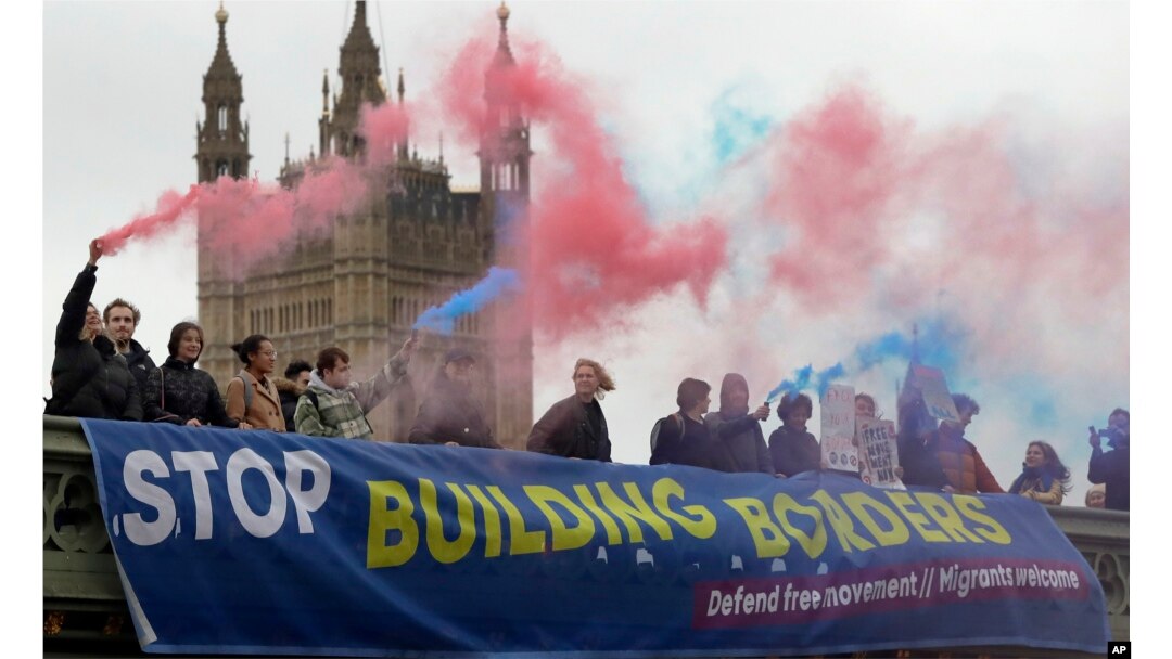 Demonstrators hold flares and a banner over Westminster Bridge in front of the Parliament buildings in London, Nov. 28, 2018. Campaigners from Another Europe is Possible and the Labor Campaign for Free Movement took part in a protest against Theresa May's Brexit deal.