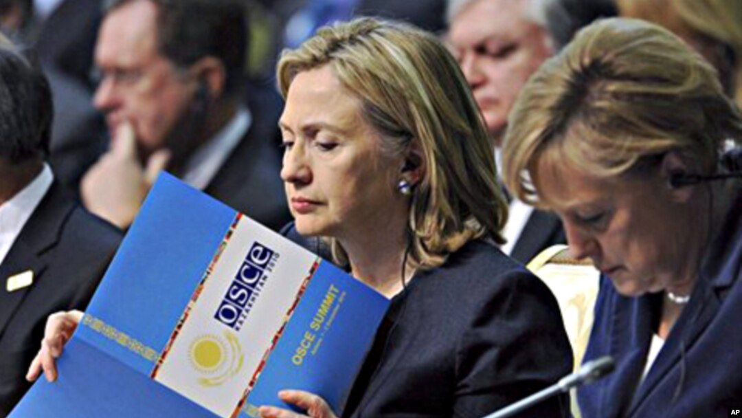 U.S. Secretary of State Hillary Rodham Clinton, center, reads a document as she sits next to German Chancellor Angela Merkel at the start of the OSCE Summit at the Palace of Independence in Astana, Kazakhstan, 01 Dec 2010