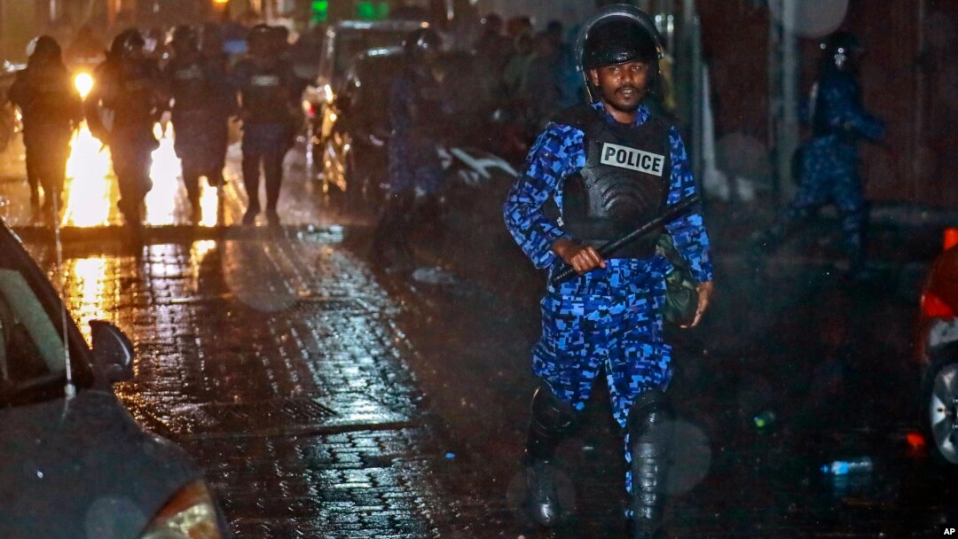 A Maldives policeman charges with a baton towards protesters after the government declared a state of emergency, in Male, Maldives, early Tuesday, Feb. 6, 2018. 