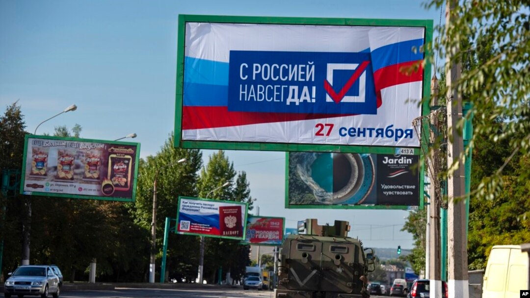 A military vehicle drives along a street with a billboard that reads: 'With Russia forever, September 27,' prior to a referendum in Luhansk, Luhansk People's Republic controlled by Russia-backed separatists, eastern Ukraine, Sept. 22, 2022.