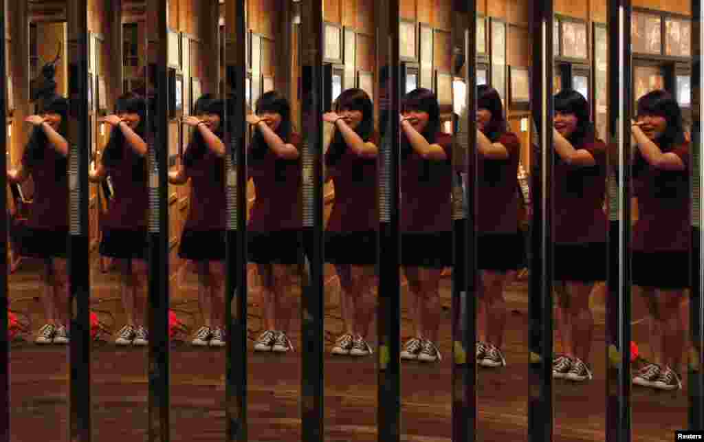 A journalist poses in front of mirrors depicting a scene in "Enter the Dragon" by the late Kung Fu legend Bruce Lee, at the Hong Kong Heritage Museum during the press preview of a five-year exhibition on Lee. Fans are marking his death 40 years ago this weekend with art gallery shows, exhibitions and even street graffiti.