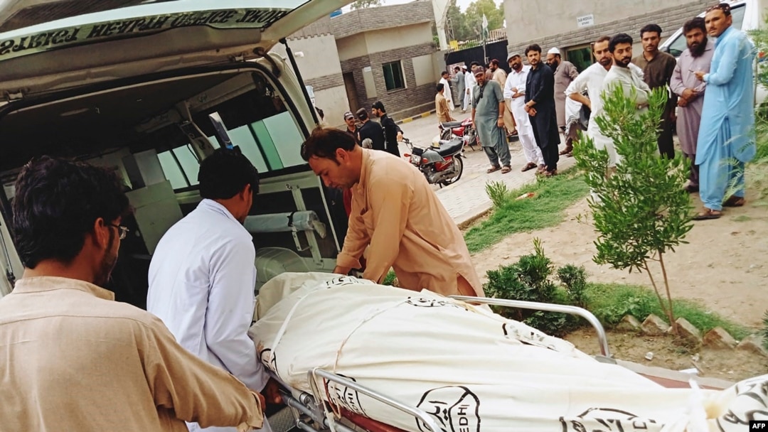 People carry the dead body of a passenger on a stretcher, who died in a bus accident, outside a hospital in Zhob district of Balochistan province on July 3, 2022