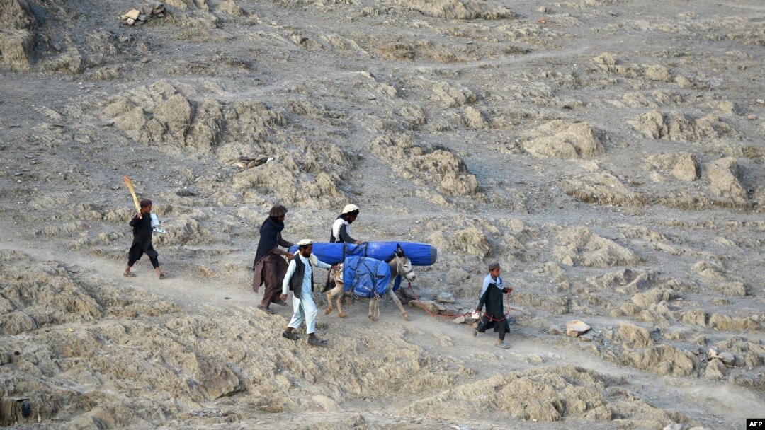 FILE - Volunteers carry aid being received from the International Organization for Migration (IOM) for recent earthquake affected people in the Afghan-Dubai village of Spera district in Khost province, June 26, 2022. 