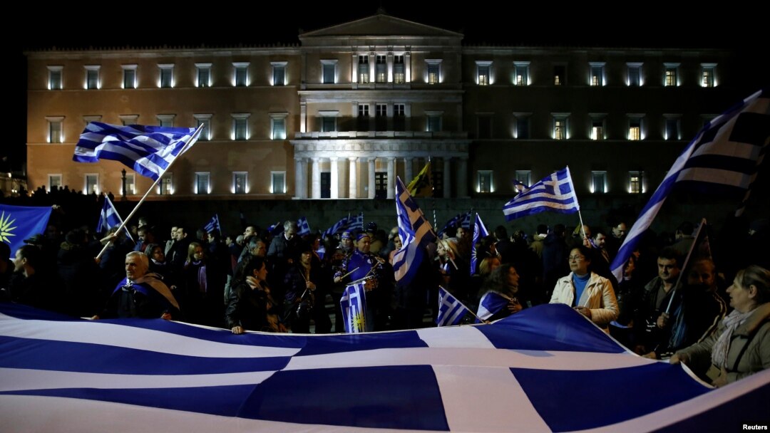 FILE - Protesters hold a giant Greek national flag during a demonstration against the agreement reached by Greece and Macedonia to resolve a dispute over the former Yugoslav republic's name, in front of the parliament building in Athens, Jan. 24, 2019.