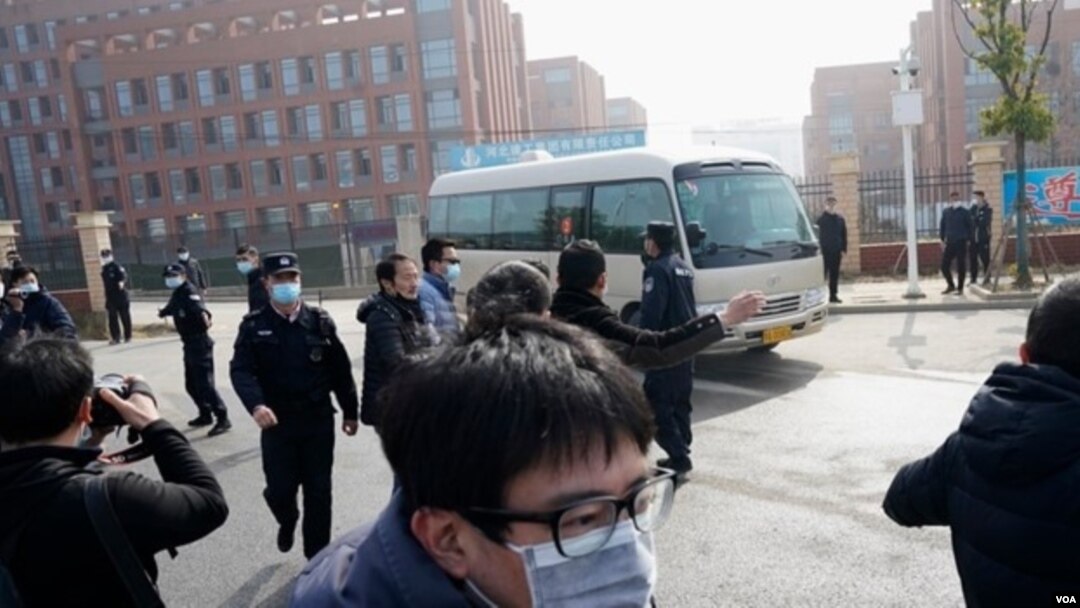 Los periodistas y el personal de seguridad se reúnen cerca de la entrada del Instituto Wuhan de Virología después de una visita del equipo de la OMS que se encuentra en Wuhan, en la provincia china de Hubei, el 3 de febrero de 2021.